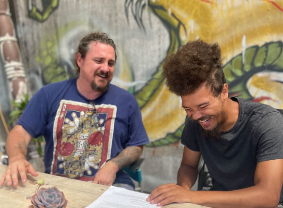 two men sitting and laughing as one receives mental health services in CA