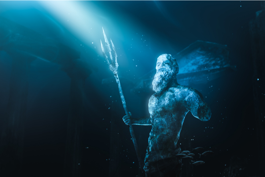 A poseidon statue featuring a bearded man holding a trident in under the sea