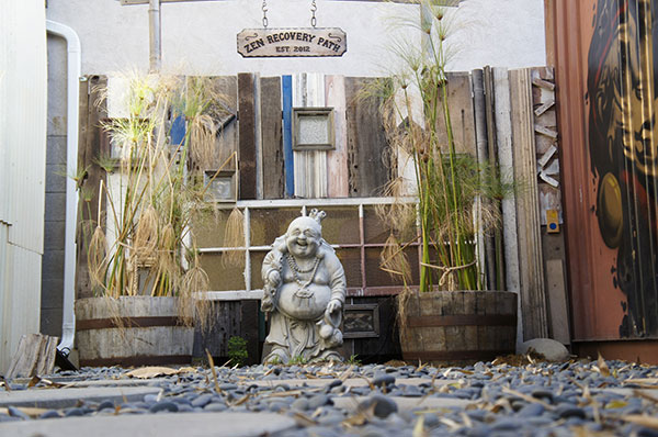 A statue of a smiling Buddha sits outside of our facility with bamboo walls