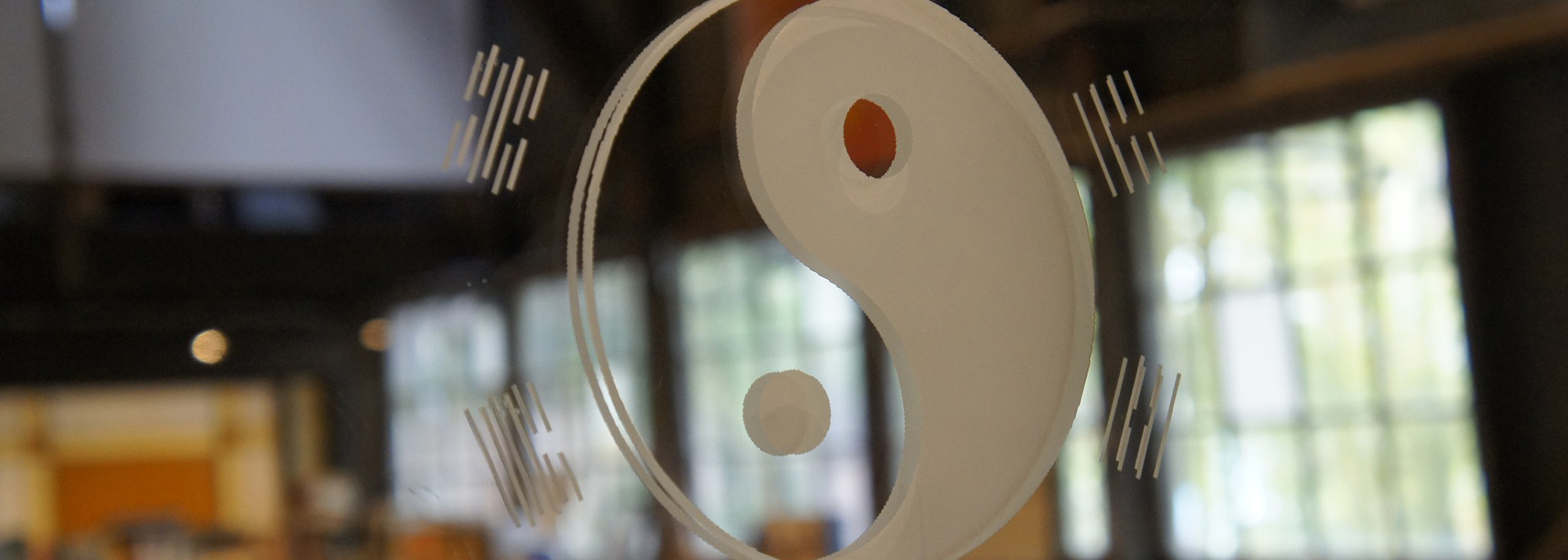 A close-up shot of a yin yang symbol etched onto a glass window inside the Barn Life Recovery building