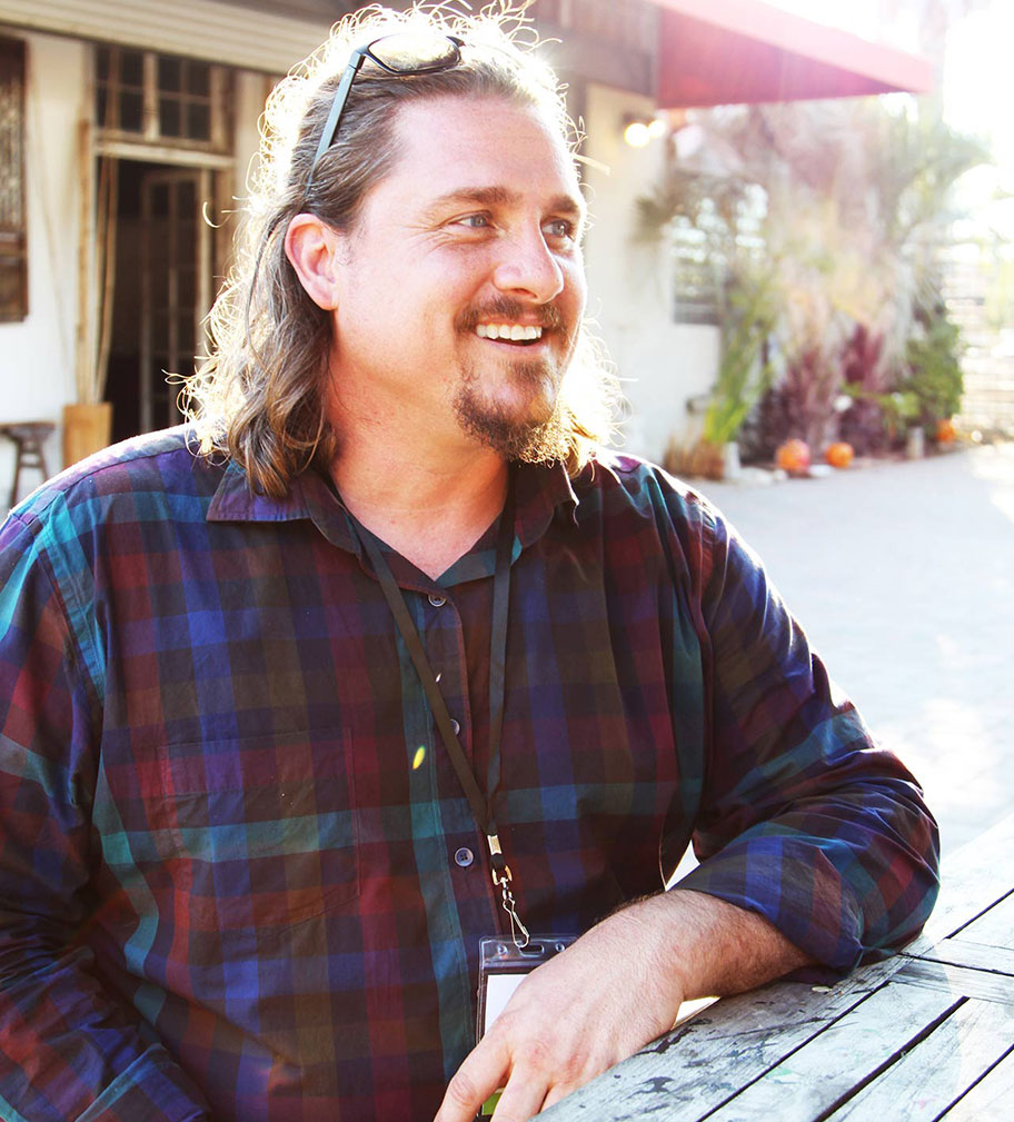 Barn Life Recovery CEO Mathew Carver, who is wearing a red-and-blue flannel, smiles while talking to a person off-screen