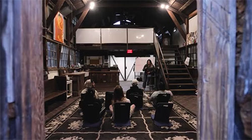 A look through the doorway of several people sitting on a rug with their backs turned during a NAMI Peer Support Group